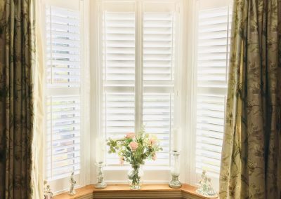 Bay window shutters in in pure white with offset tilt rods. Supplied and installed by Signature Window Shutters Newcastle upon Tyne, North East England